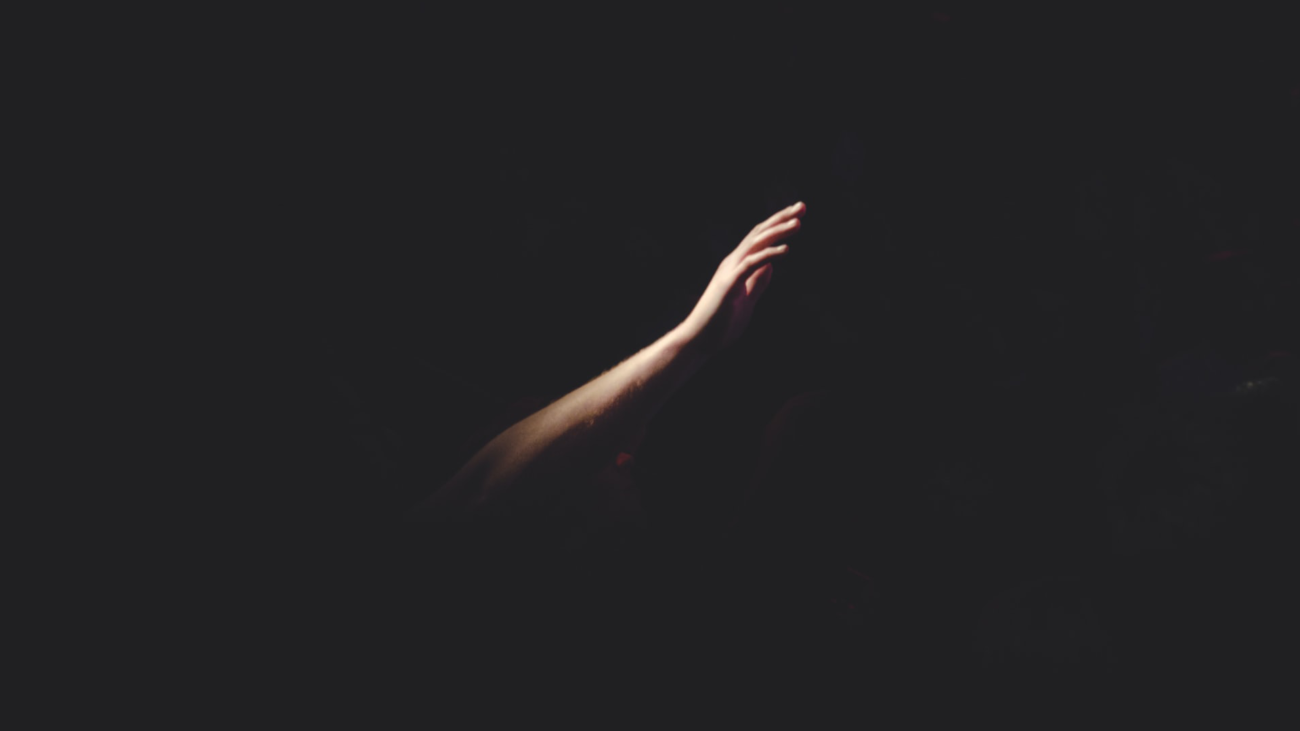 an illuminated hand reaching out into darkness