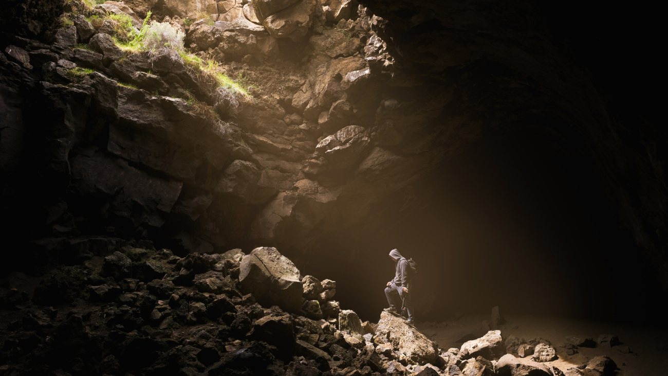 a man standing in a cave, lit from above